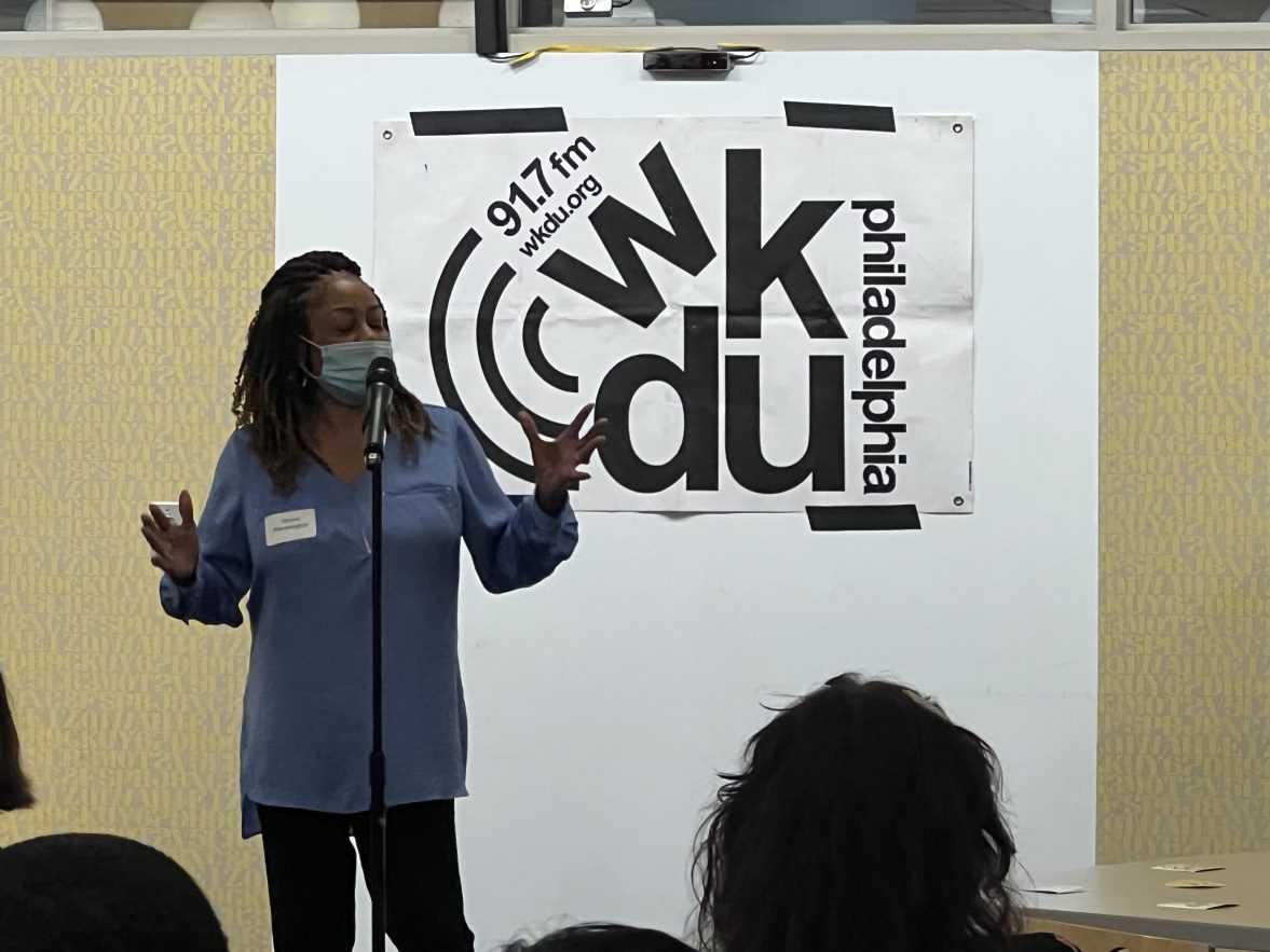 A woman stands in front of a large WKDU banner during the WKDU opening event